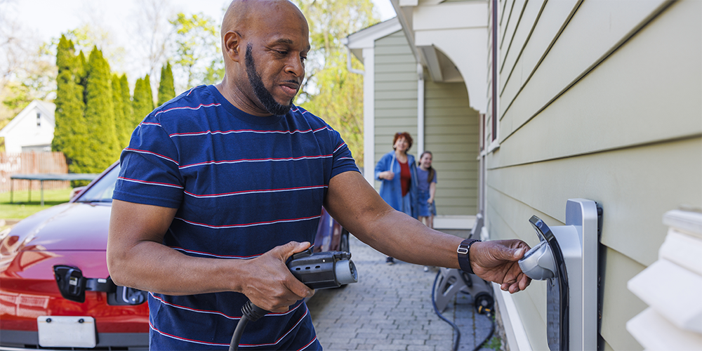 Photo of man plugging car charging cable into charger